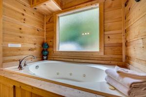 Lazy Bear Lodge by American Patriot Getaways في Oldham: حوض استحمام في حمام خشبي مع نافذة +30 صورة