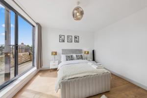una camera bianca con un letto e una grande finestra di Hobson Woods Apartments a Londra