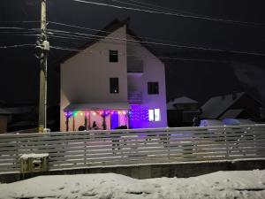 a building with purple lights in front of a fence at La Oprescu in Azuga +11 photos