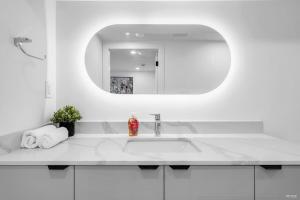 ein weißes Badezimmer mit Waschbecken und Spiegel in der Unterkunft Peaceful 2 Bedroom 2 Baths Airb&b in Shaughnessy in Vancouver + 17 Fotos