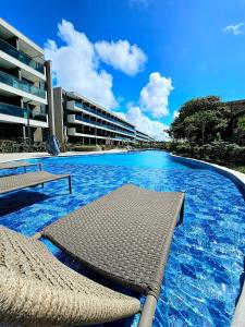 a swimming pool with two chairs and a building at Luxuoso e sofisticado Beach Class Summer by HM in Porto De Galinhas