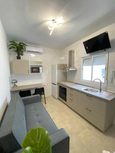 a kitchen and living room with a couch and a table at Apartamentos SOL y ARENA in Almería +17 photos