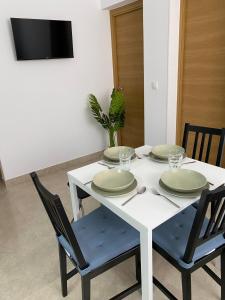 a white table with four chairs and plates on it at Apartamentos SOL y ARENA in Almería