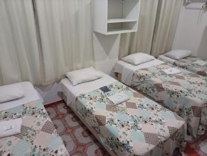 a room with three beds with quilts at Hotel Pousada Central Campo Grande in Campo Grande