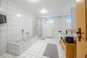 a white bathroom with a tub and a sink at Ferienwohnung am Feld Winterbach in Sankt Wendel