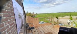 a deck with a chair and a view of a field at Pipowagen bij Sneek, voor maximaal 2 personen in Hommerts