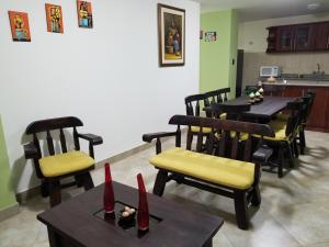a dining room with tables and chairs and a kitchen at Cómodo apartamento con aire puro y vista panorámica ideal para turistas in Ambato