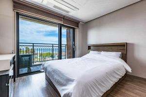 a bedroom with a large bed and a large window at Goraesu Pension in Seogwipo