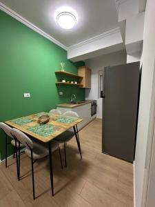 a kitchen with a table and a green wall at Papa's Apartment in Korçë