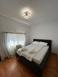 una camera da letto con un letto grande con lenzuola bianche di Apartament Cozy a Gherla