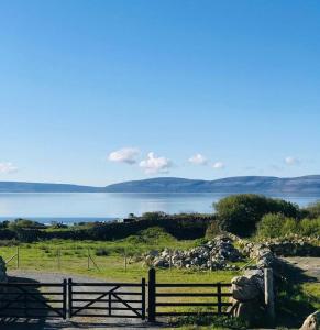 a fence on a field with a view of a lake at Lavender Lane Country cottage , Furbo in Galway