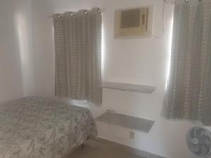 a small bedroom with a bed and two windows at Descanso e aconchego massaguacu in Caraguatatuba