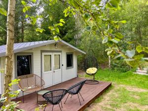 a cabin with chairs and a table on a deck at Baltic Beach Charm Tiny House C in Pērkone