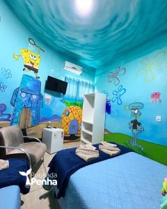 Una habitación con una cama con una pared azul con dibujos animados. en Pousada Penha Beto Carrero, en Penha