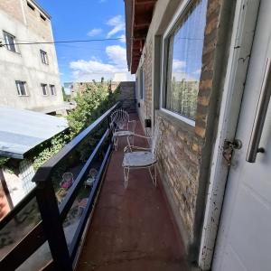 a balcony with two chairs and a window at Alojamientos Copihue in Zapala