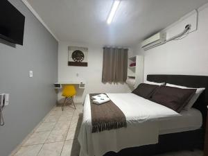 a bedroom with a bed and a yellow chair at GOLDEN ROSE HOTEL in Campinas
