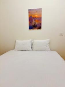 Elegant Downtown Escape في القاهرة: سرير بملاءات بيضاء ولوحة على الحائط