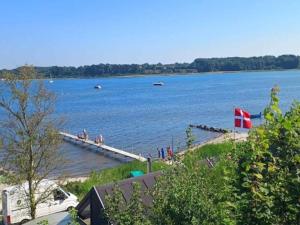 a large body of water with a dock and a flag at 6 person holiday home on a holiday park in Hejls in Hejls