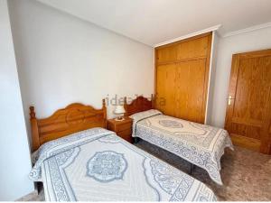 a bedroom with two beds and a wooden cabinet at Oasis house in Arenales del Sol