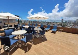 a rooftop patio with tables and chairs and umbrellas at Studio Smart lindo e funcional in Salvador