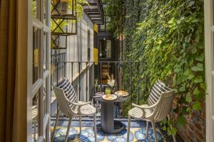 a patio with three chairs and a table on a balcony at Roso Guest House in Mexico City