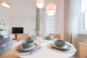 un comedor con una mesa blanca con platos y copas de vino en nJoy! Federsee Getaway - Therme & Balkon, en Bad Buchau