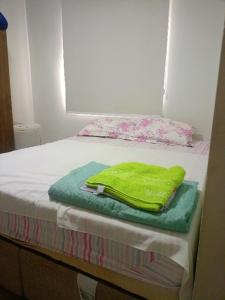 a green towel sitting on top of a bed at Lar de charme e tranquilidade em montes Claros in Montes Claros