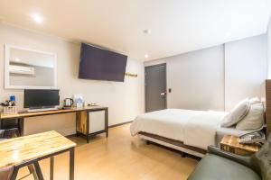a hotel room with a bed and a desk with a television at illuwa M in Seoul