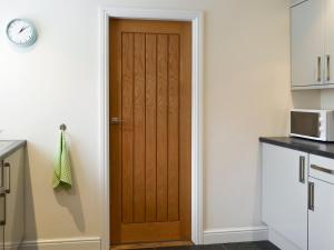 a wooden door in a kitchen with a clock at Mews Cottage in Bridlington