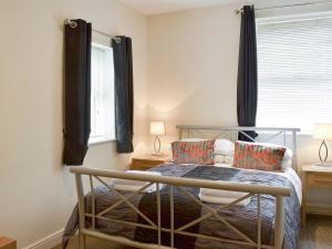 a bedroom with a bed and two lamps and a window at Mews Cottage in Bridlington