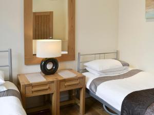 a room with two beds and a table with a lamp at Mews Cottage in Bridlington