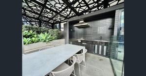 a table and chairs on a patio with a building at Modern 2BR, Swimming Pool, Gym & Parking in Melbourne