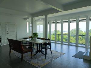 a dining room with a table and chairs and windows at Panoramic View & Spacious with Swimming Pool Aza Sunset Villa 1 in Langkawi Intl