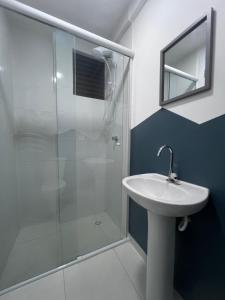 a bathroom with a glass shower and a sink at Studio charmoso no coração de Curitiba! in Curitiba