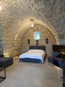 a bedroom with a bed and a stone wall at Yassmina Guest House in Maasser El Chouf