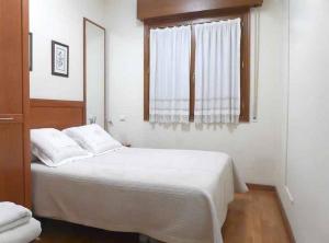 a bedroom with a white bed and a window at Pensión USOA in Zubiri