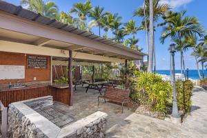 a patio with a table and a bench and the ocean at Casa Aloha Designer Condo w Oceanfront Pool in Kailua-Kona