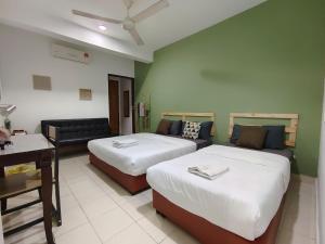 a hotel room with two beds and a couch at Suite Us Guesthouse Kubang Kerian in Kota Bharu