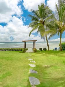 a pathway to the beach with a gazebo and palm trees at Caribbean Beachfront Living, Apartment in Juan Dolio