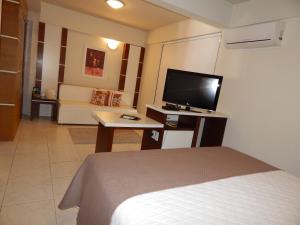 a hotel room with a bed and a flat screen tv at Altadomo Hotel in Santa Maria