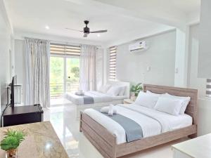 a bedroom with two beds and a television in it at INATO SUITES Rm 2 2 queen beds in Panglao