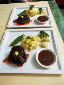 two plates of food with meat and vegetables and dipping sauces at SELA Bungalow and Italian Restaurant in Koh Rong