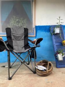 a black folding chair sitting in front of a blue wall at Halima Guesthouse in Larache