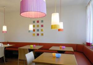 ein Restaurant mit Tischen, Stühlen und Hängelampen in der Unterkunft Business & Budget Hotel Tessin in München