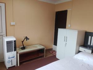 a bedroom with a bed and a desk with a lamp at Annapurna View Apartment in Pokhara