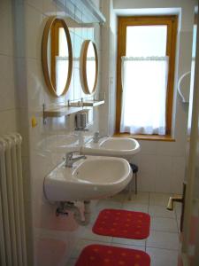 dois lavatórios numa casa de banho com dois espelhos em Ostello SanMartino em San Martino di Castrozza