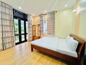 a bedroom with a bed with white sheets and windows at PU Homestay in Hue