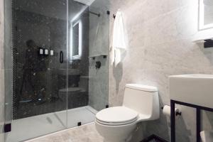 ein Badezimmer mit Toilette und Glasdusche in der Unterkunft El Louis - King Room-Pool - Resort Vibe Near Beach in San Juan
