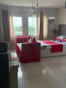 a bedroom with a bed and a couch and windows at spacious condo unit 1P olvera residences in Bacolod