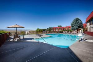 a large swimming pool with an umbrella and chairs at Red Lion Hotel Pendleton in Pendleton